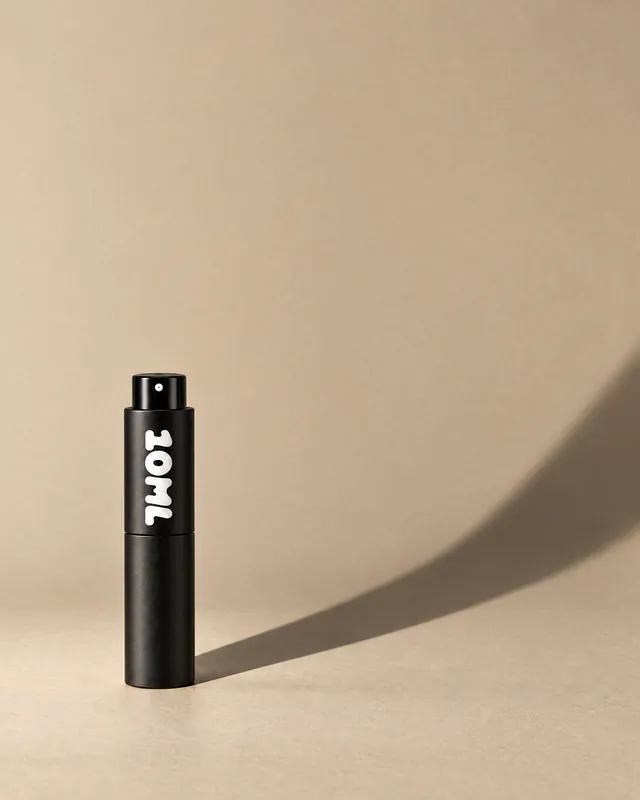 A black 10ML atomiser casting a long shadow on a sand-coloured wall