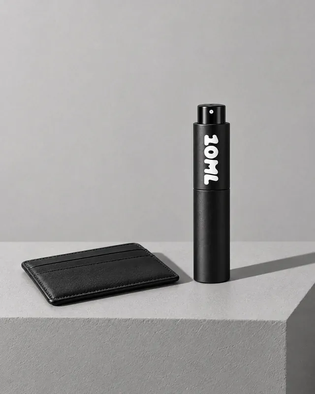 A black 10ML atomiser beside a leather card holder on a grey plinth