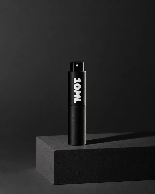 A black 10ML atomiser on a black stone block in low light