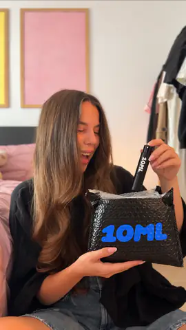 Usměvavá žena vytahuje černý rozprašovač 10ML ze zásilkové obálky 10ML